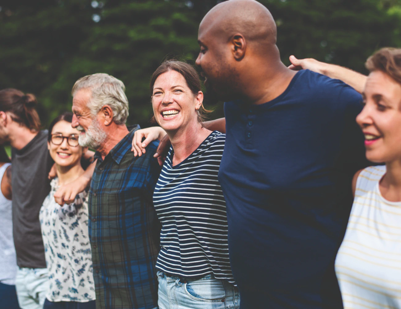 A group of people standing smiling with their arms around each others shoulders