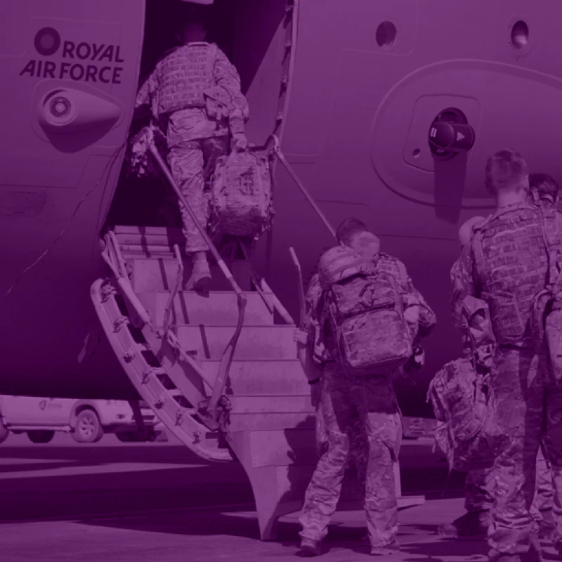 Military personnel in uniform carrying kit bags boarding an RAF transport aircraft.